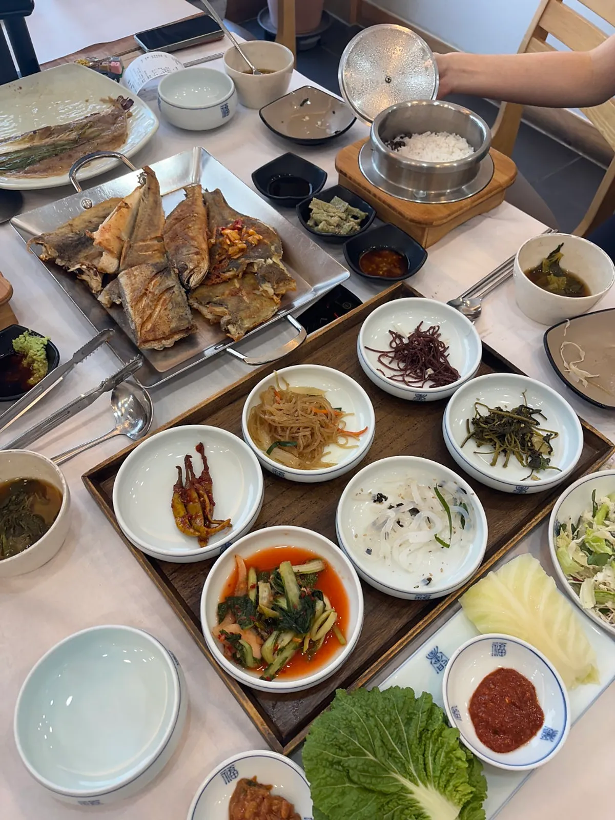Table set with banchan and grilled fish
