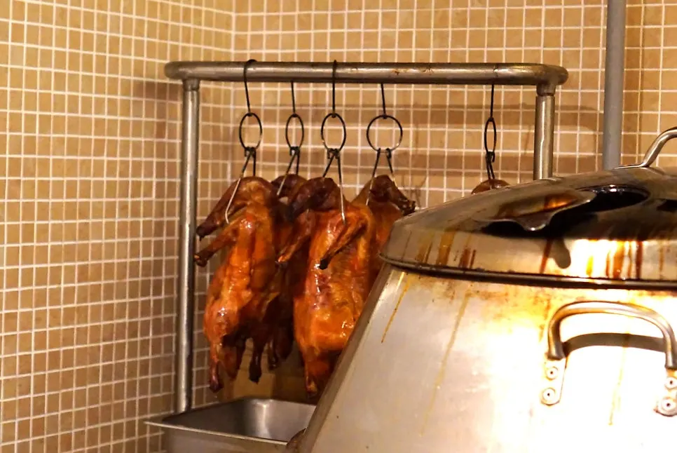 Peking ducks hanging to dry in the open kitchen