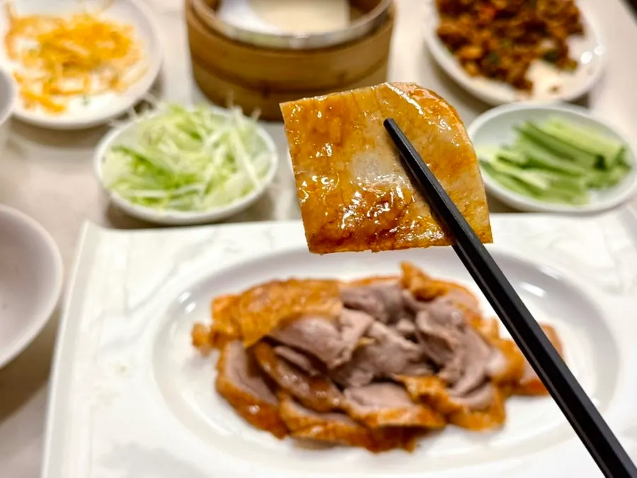 Pancake topped with Peking duck, scallion strips, and cucumber