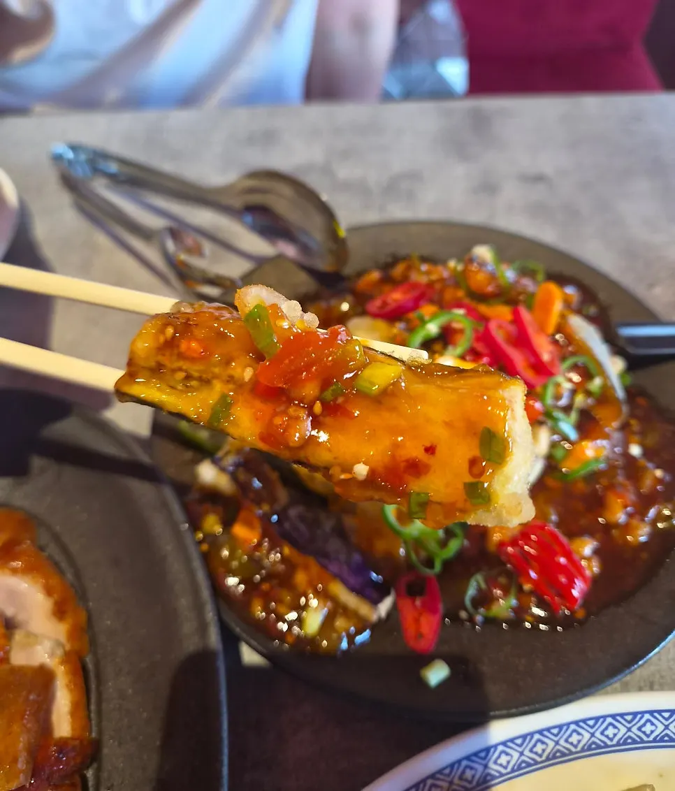 A piece of eggplant fritter enjoyed as a drinking snack