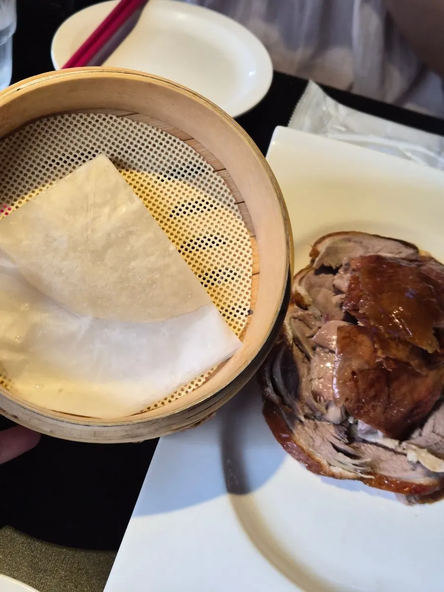 Peking duck plated with side vegetables and sauce