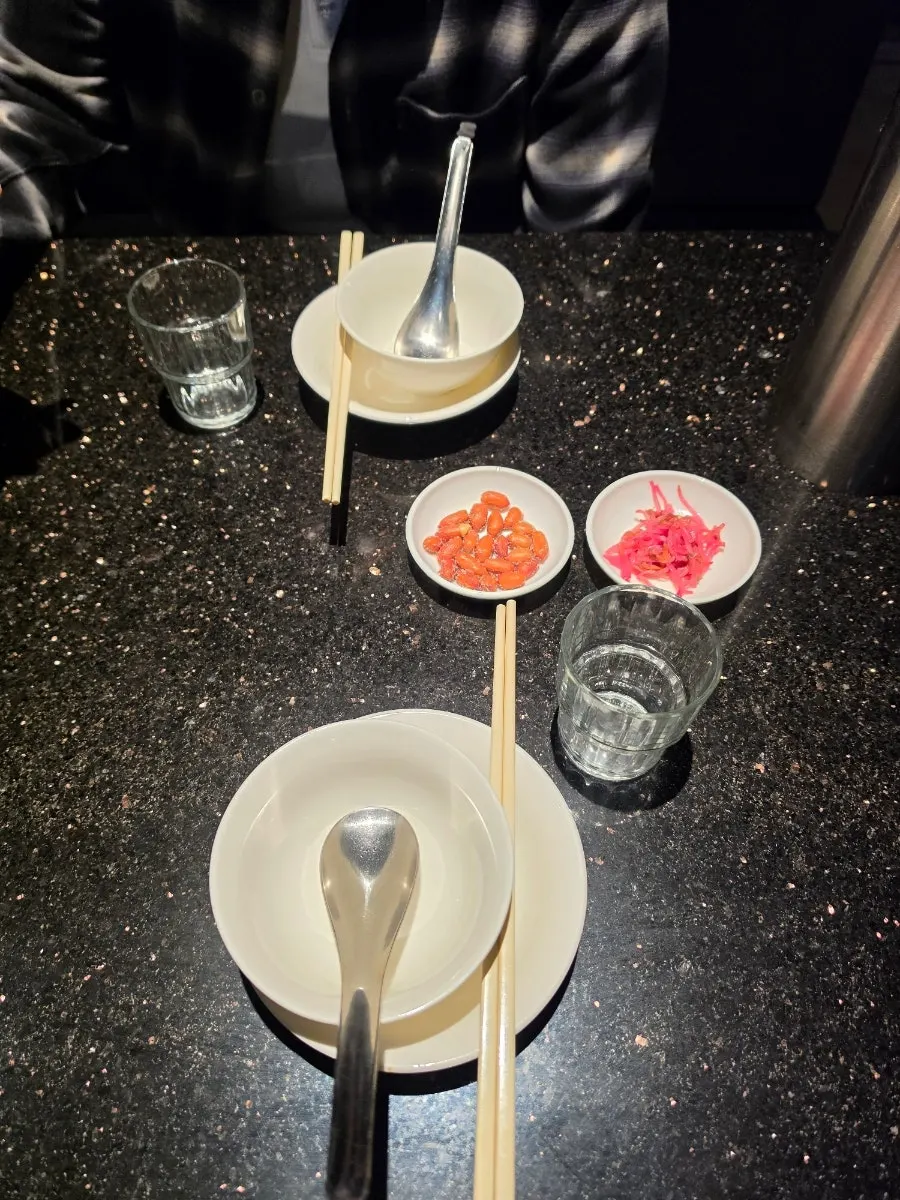 Side dishes of pickled bean sprouts and sugared peanuts