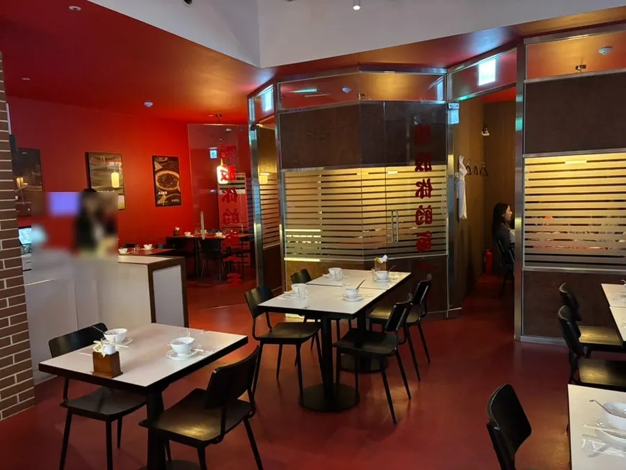Seating toward the back of the restaurant with white tables and black chairs