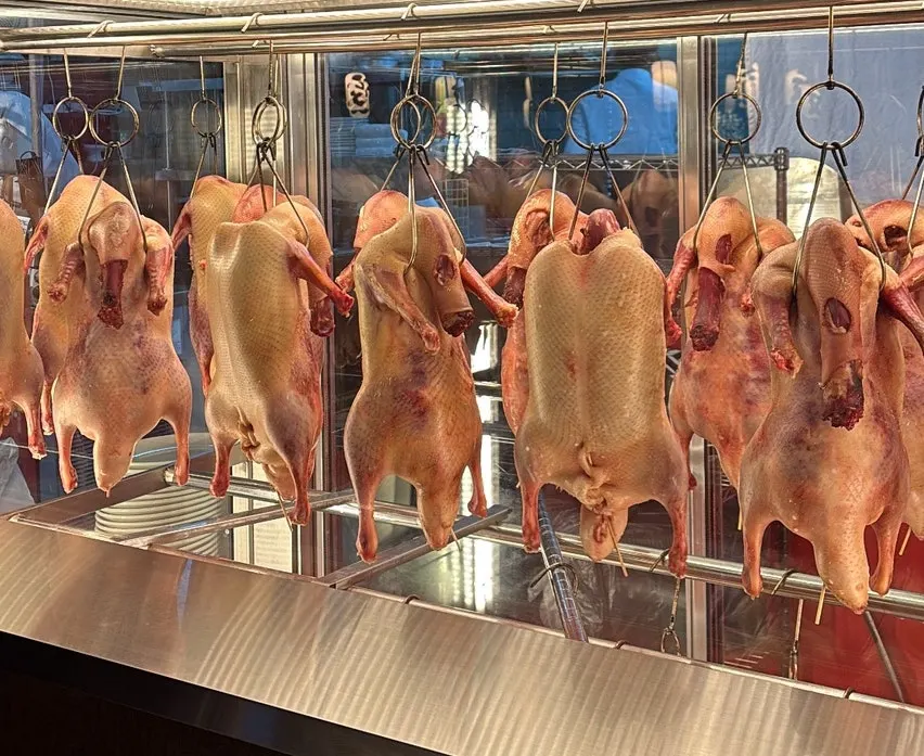 Prepared ducks hanging in a row on one side of the restaurant