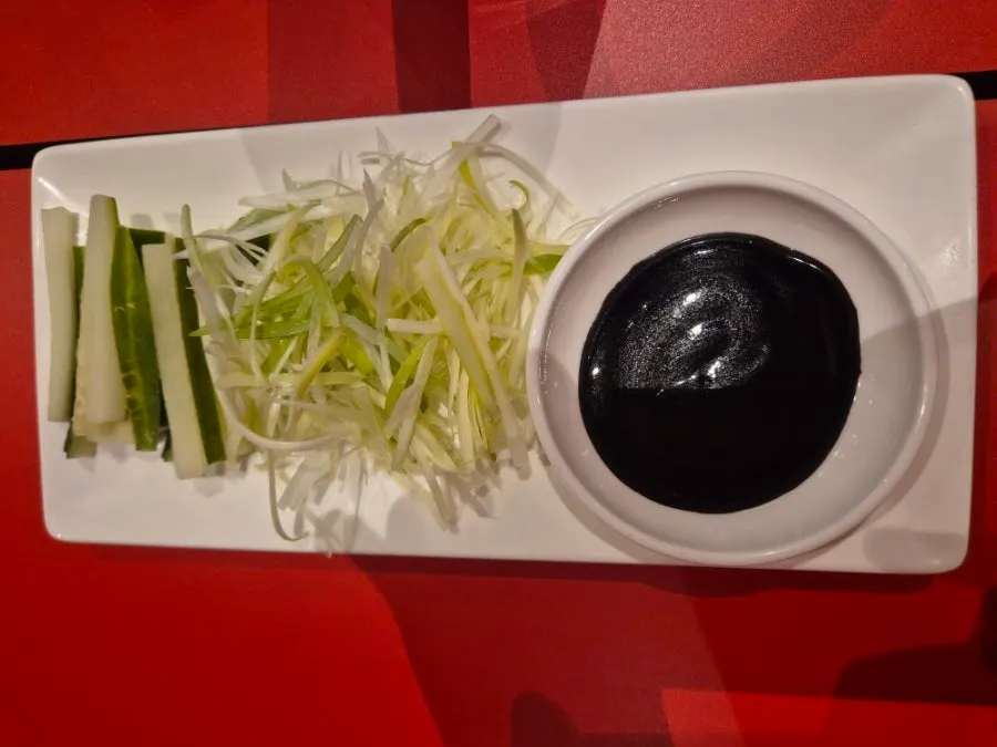 Thinly sliced Peking duck skin and meat served on a plate