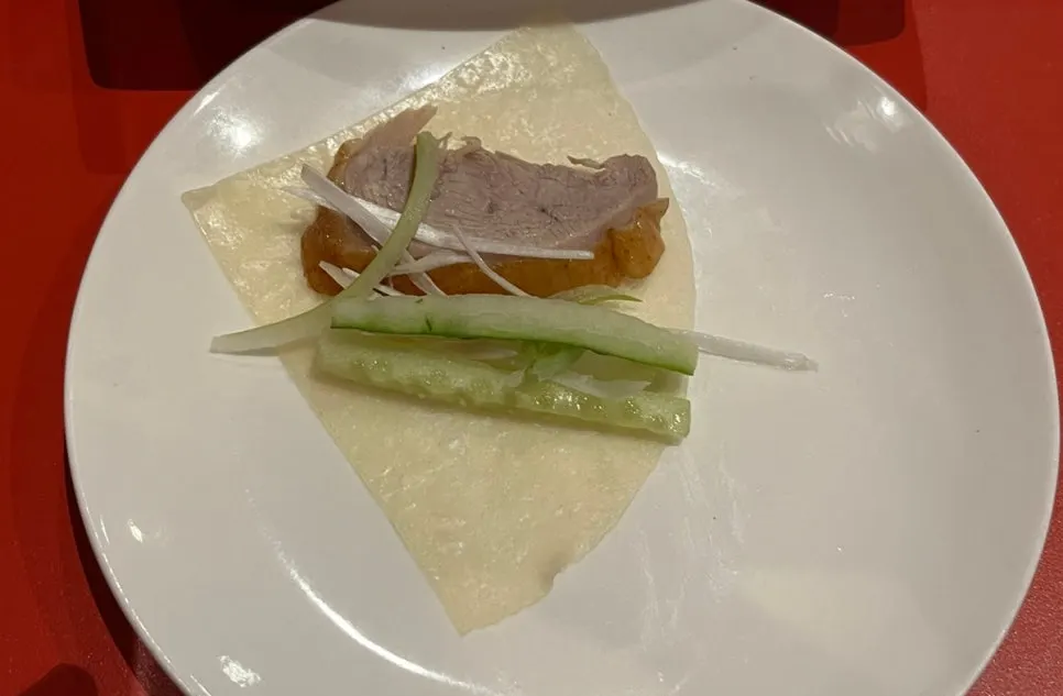 Peking duck table setting with wheat pancakes, cucumber, and scallion