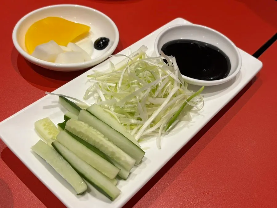 Plate of pancakes, cucumber, scallion strips, and sauce