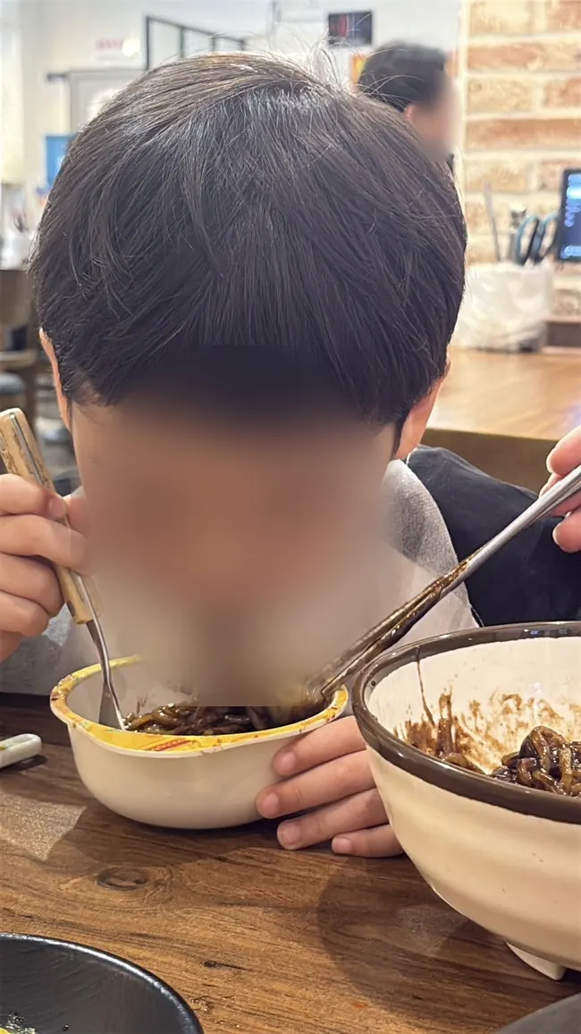 A child eating jajangmyeon on her own