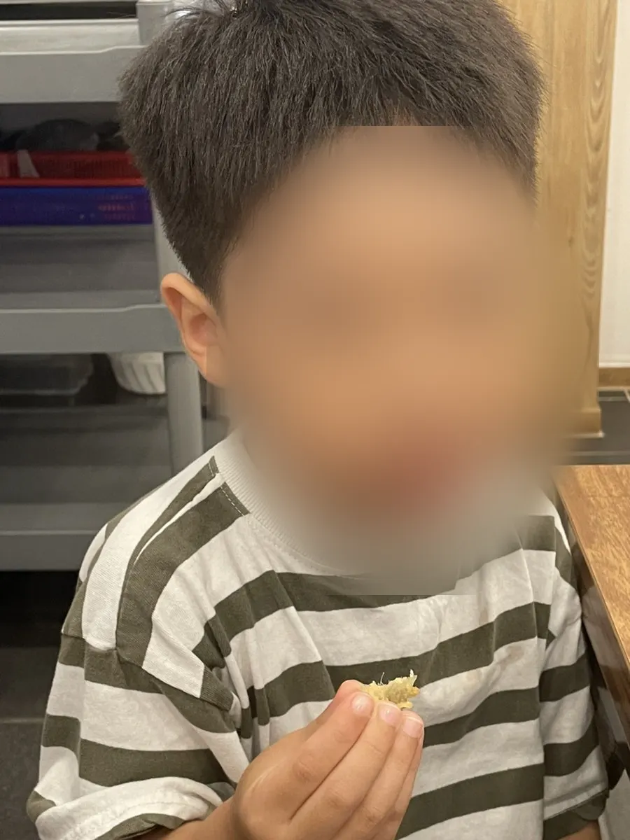 A child eating fried loach by hand