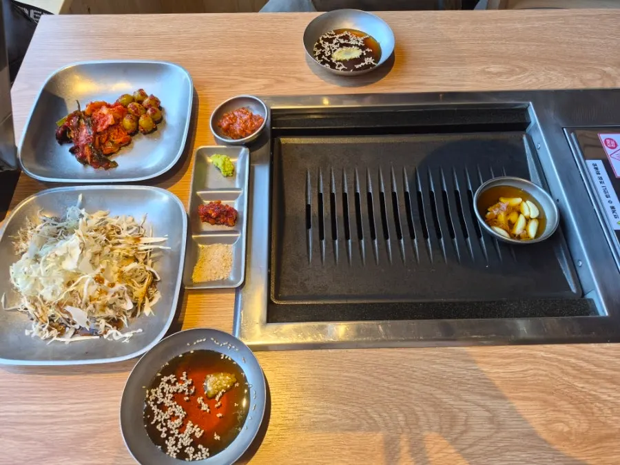Basic table setting with salad, kimchi, green onion kimchi, and olives
