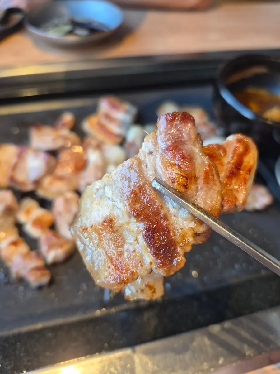 A grilled piece of pork belly topped with salted shrimp