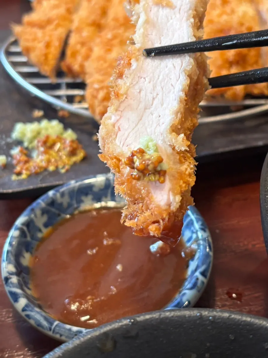 Sepotong donkatsu dicelup saus
