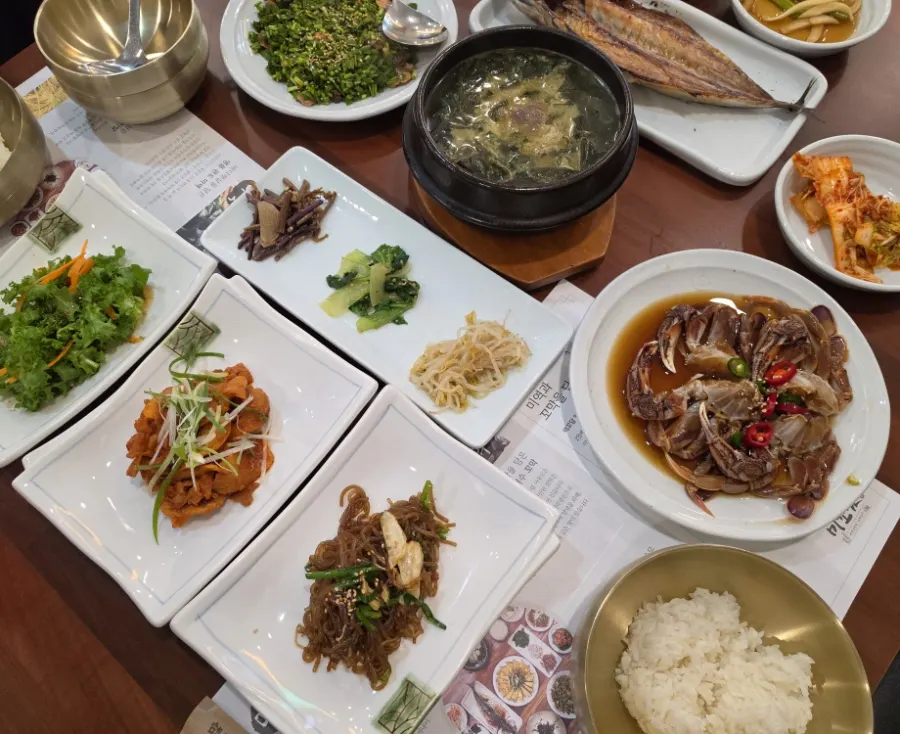 Side dishes including stir-fried pork, japchae, and lettuce wraps