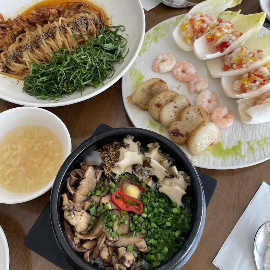 Table spread with pot rice, pasta, and grilled scallop dishes together
