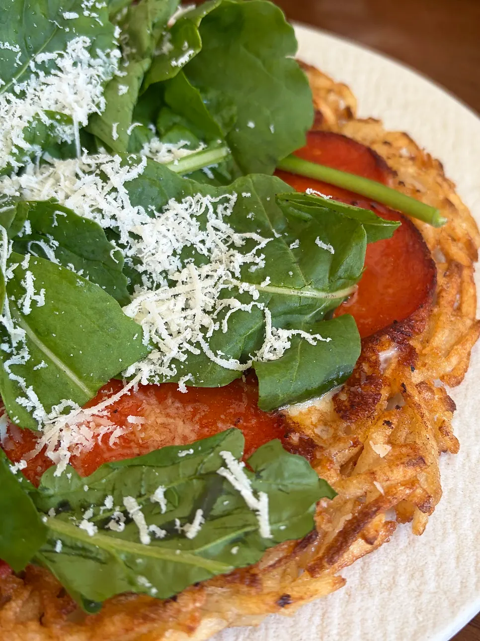 Potato pancake topped with pepperoni and arugula