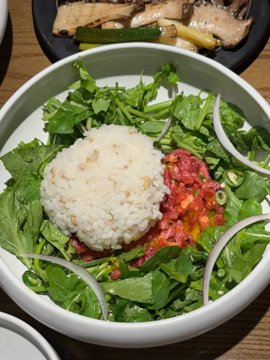 A spoonful of yukhoe bibimbap mixed with minari and seasonal vegetables