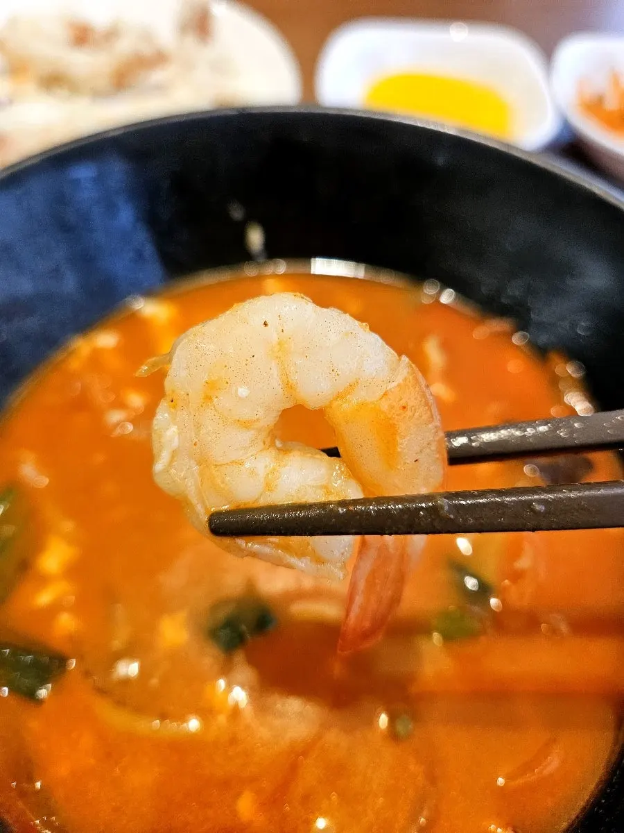 A spicy bite of sundubu jjampong on chopsticks