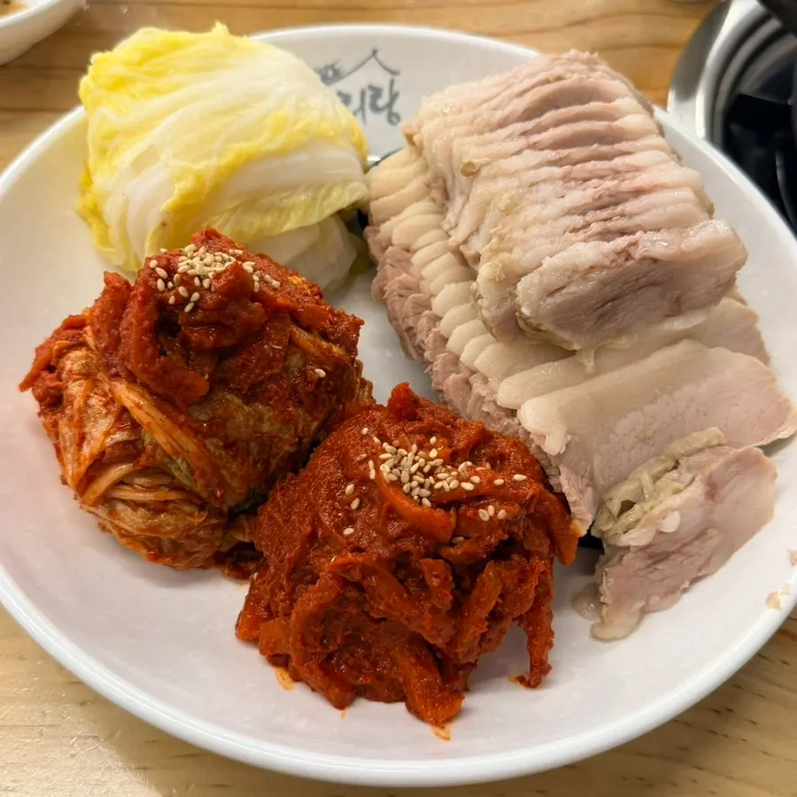 Plate of half-and-half bossam topped with bossam kimchi and radish kimchi