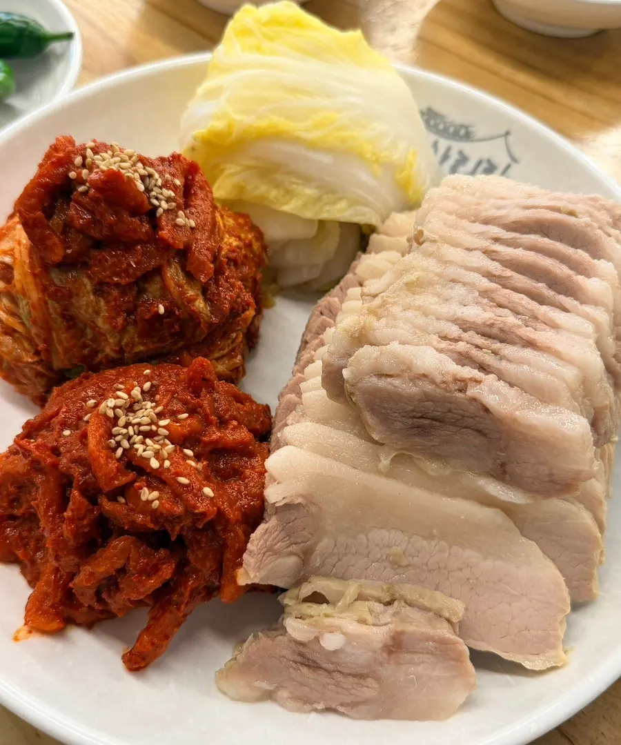 A single wrap of bossam meat topped with bossam kimchi