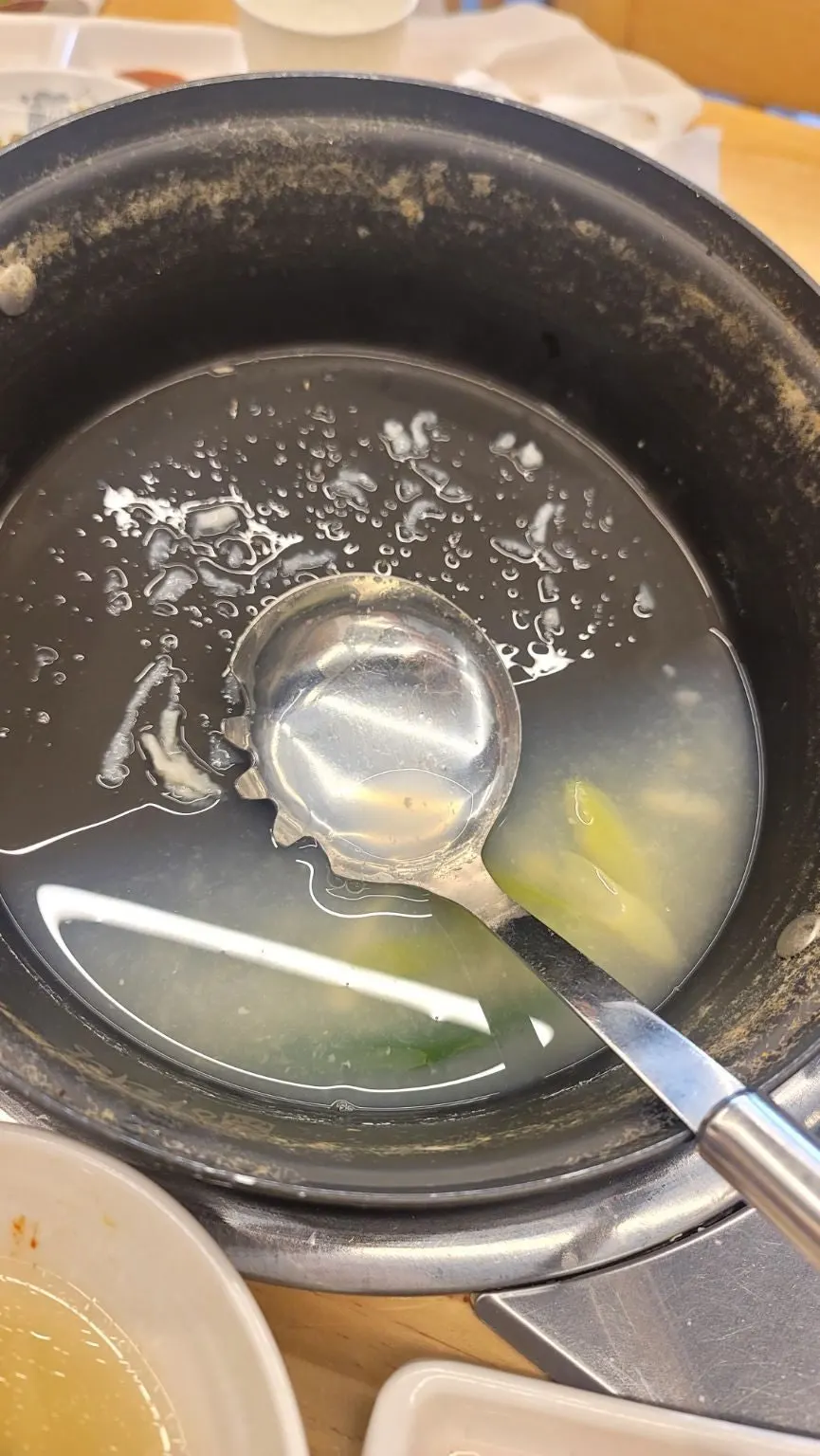 Noodles and clams lifted up with a ladle