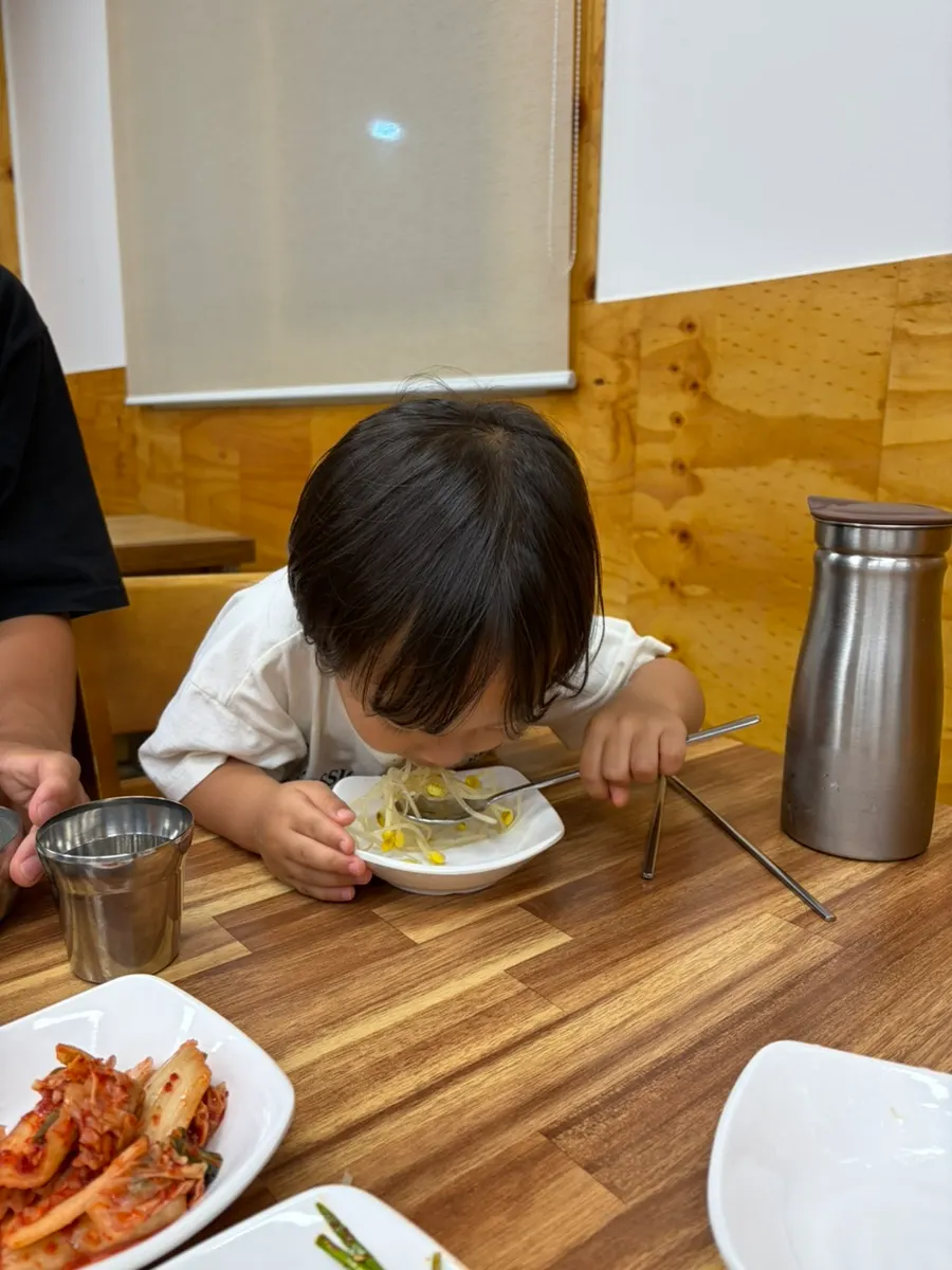 Bean sprout side dish eaten straight off the plate by a child