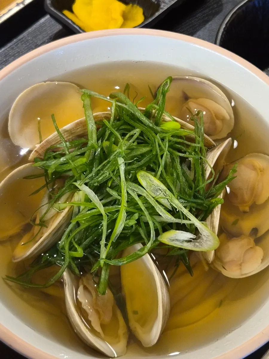 A bowl of clam udon topped with clams