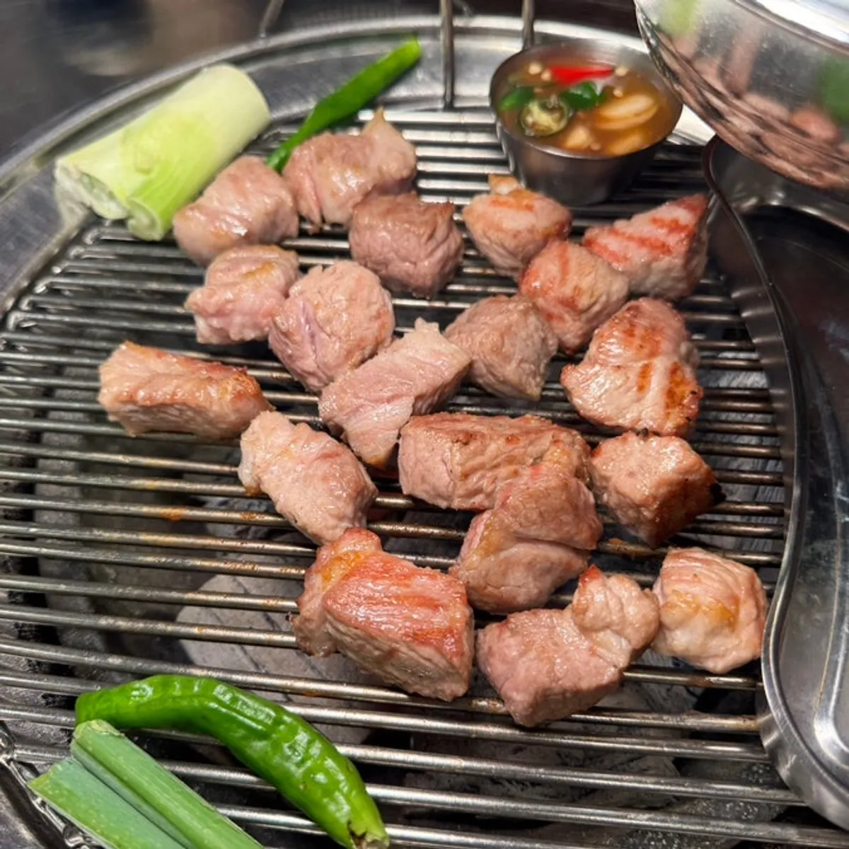 Thick-cut pork neck grilling over charcoal