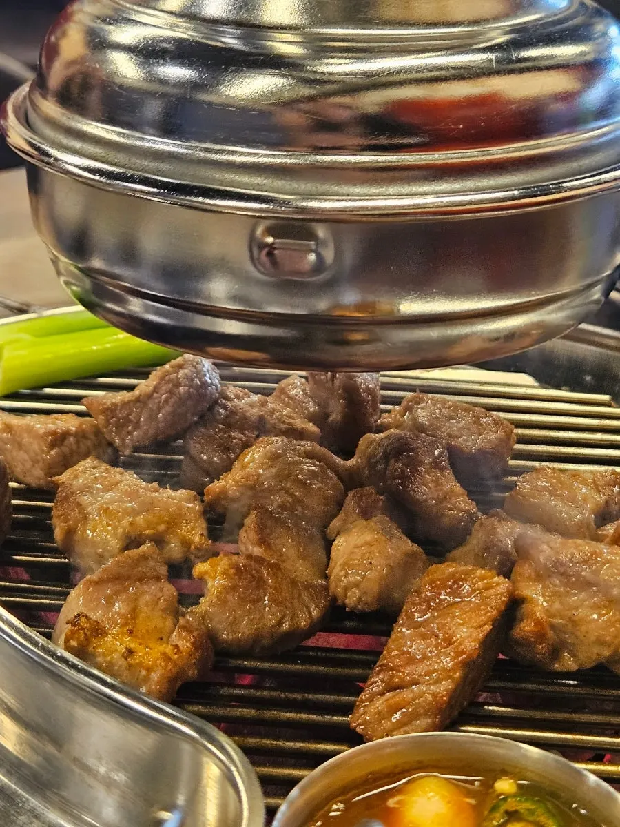 Pork neck grilling over charcoal