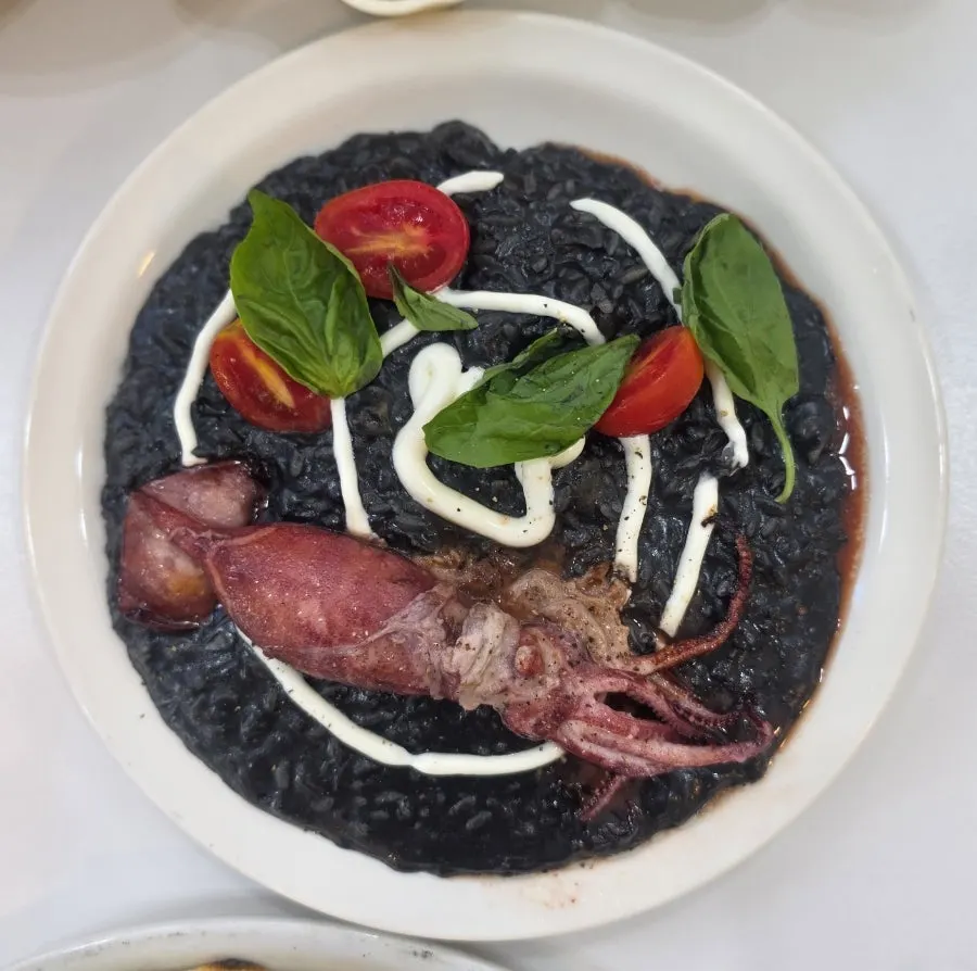 Squid ink risotto topped with a whole squid