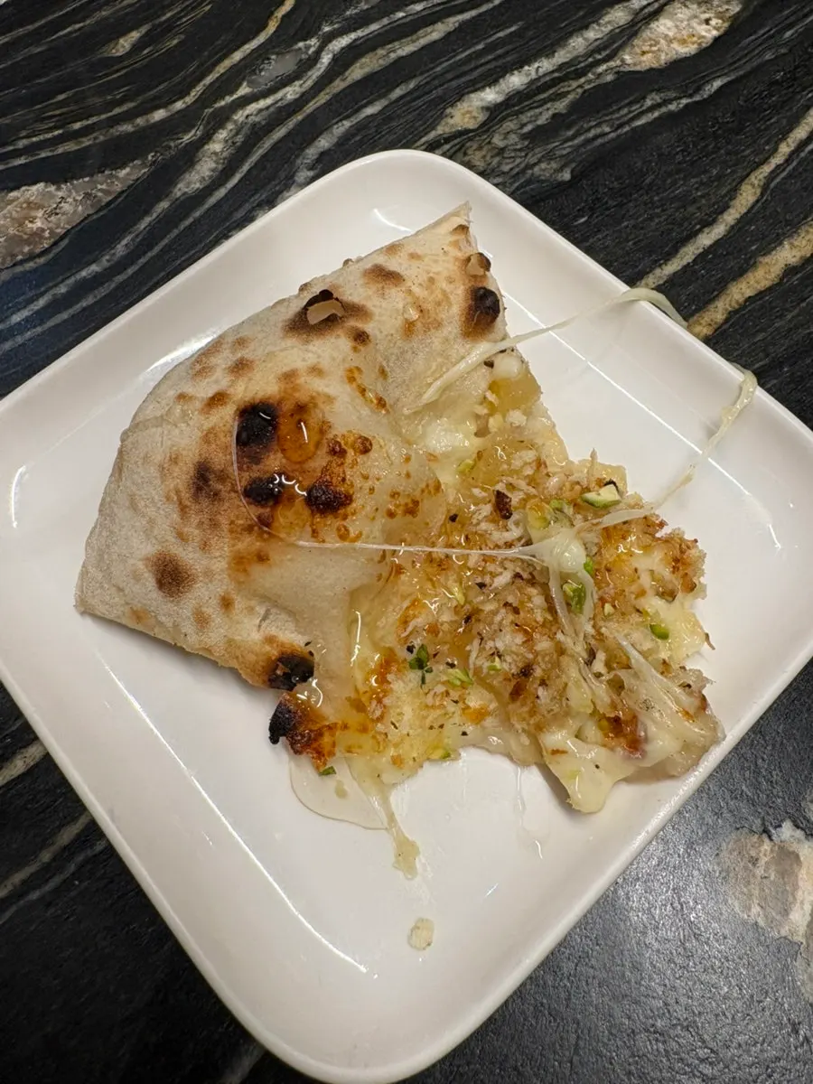 Cheese stretching from a slice of apple gorgonzola pizza
