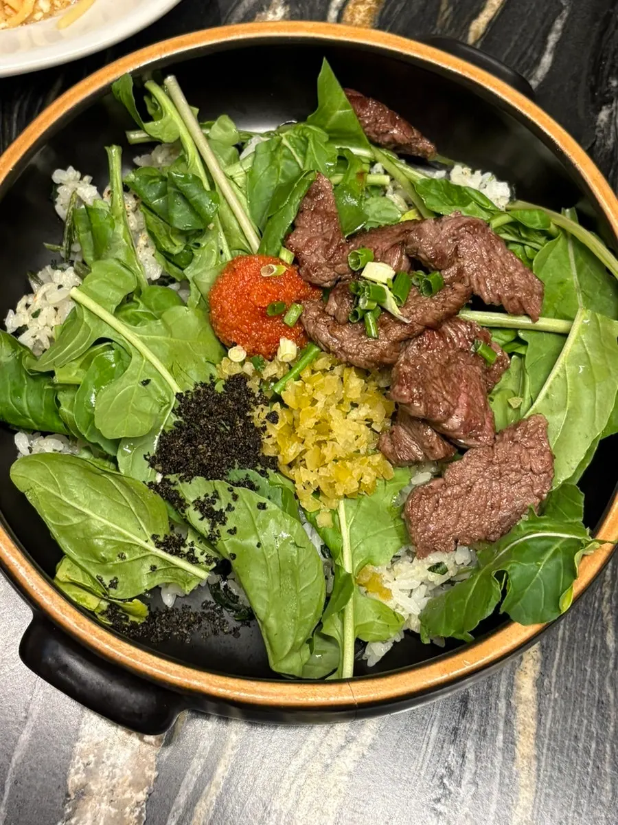 Steak bibimbap topped with vegetables and meat