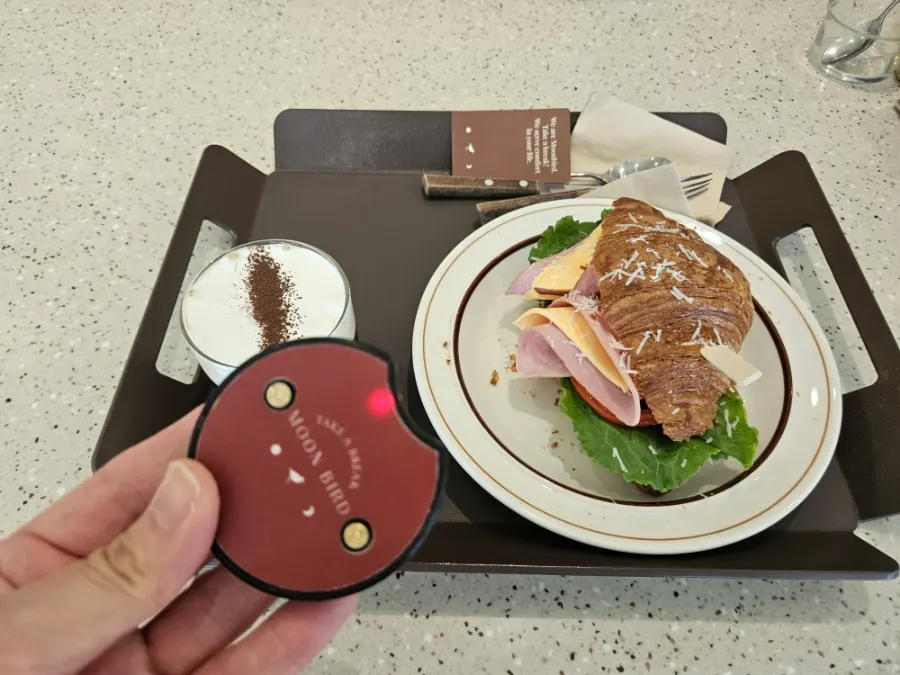 통창 앞 테이블의 크로와상 샌드위치와 아인슈패너