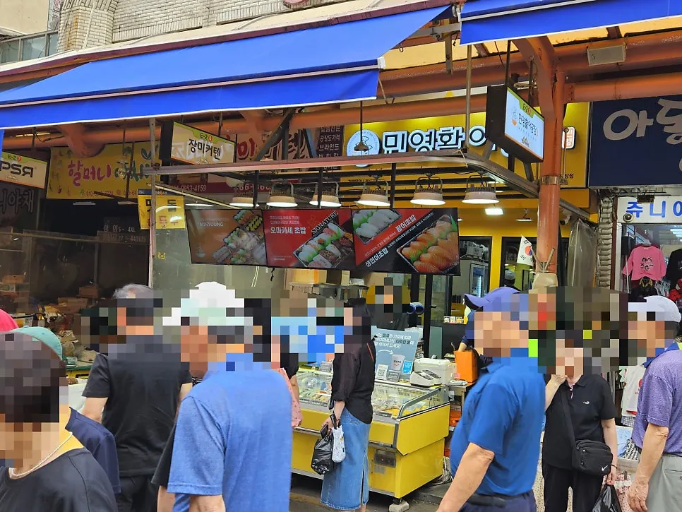 Exterior of Minyeong Hwareo Gongjang Moraenae Market Branch crowded with customers on a Saturday afternoon