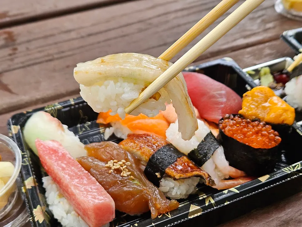 A piece of engawa sushi held with chopsticks