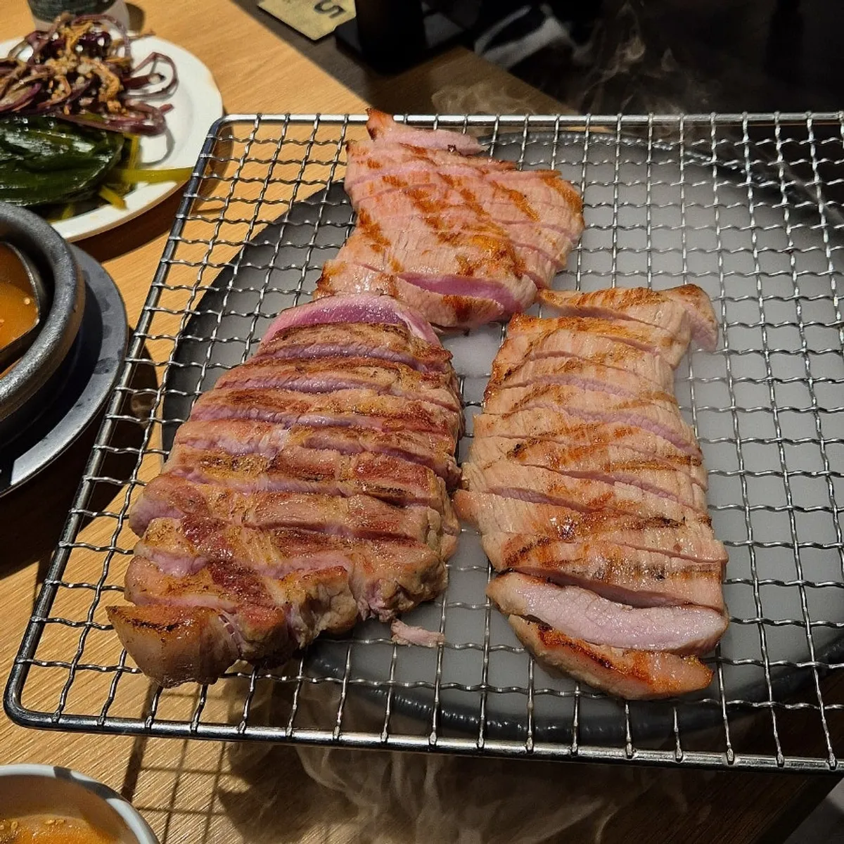 Owner slicing pre-grilled meat on a cutting board at the table