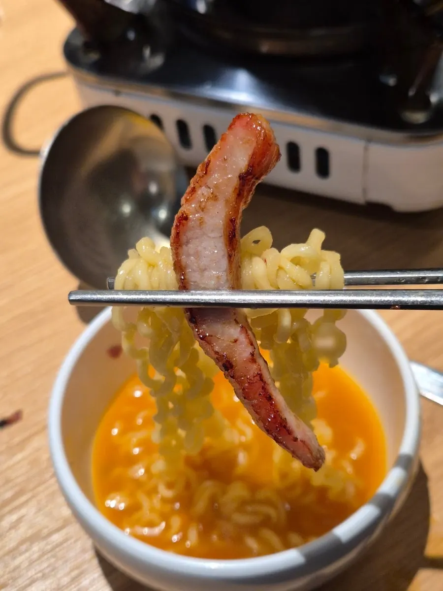 Grilled meat placed on top of the bone-broth ramen