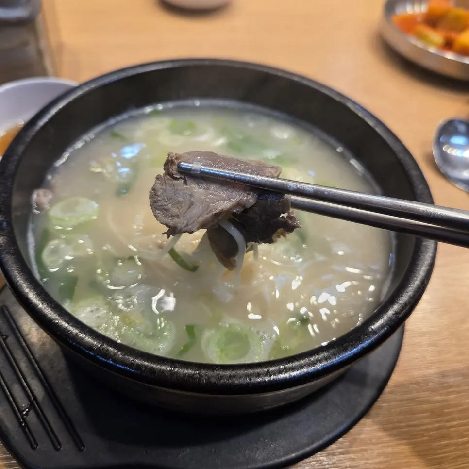A piece of seolleongtang meat lifted with chopsticks