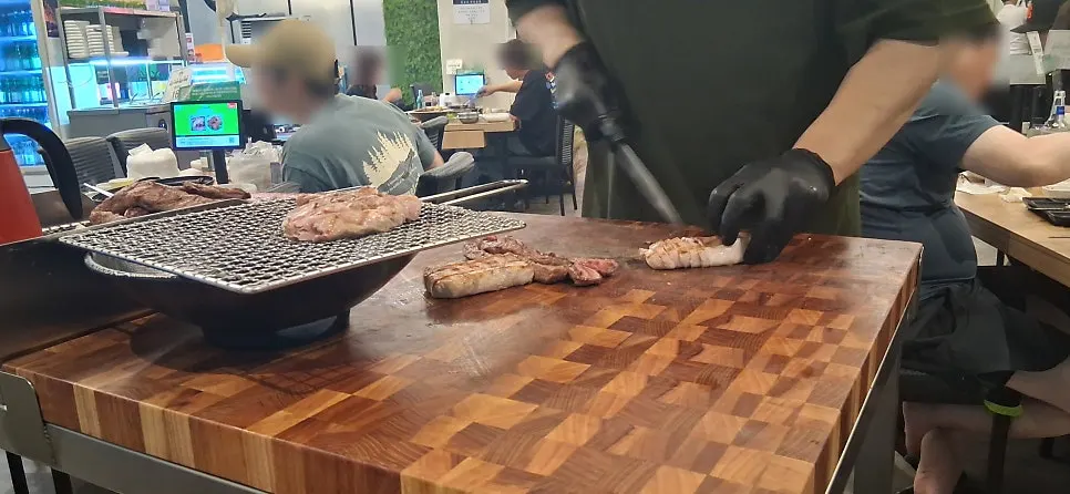 Owner slicing pre-grilled meat on a cutting board