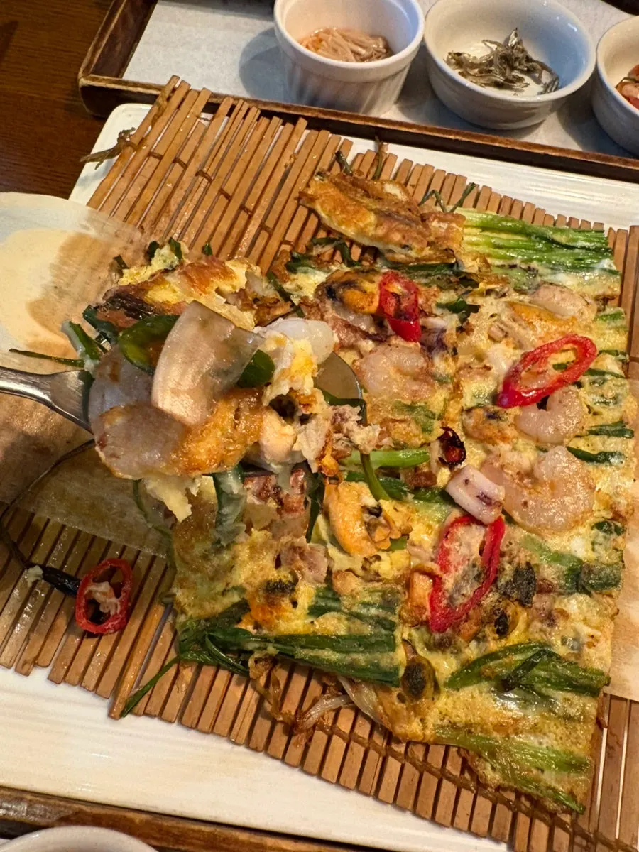 A piece of seafood pancake dipped in onion-chili soy sauce