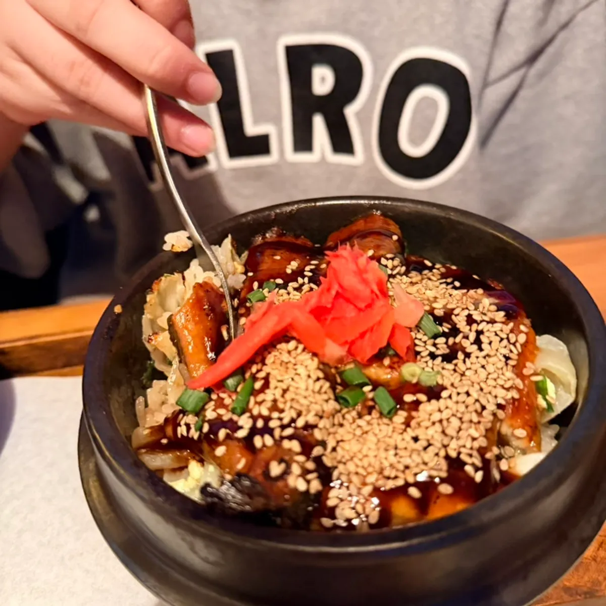 A bite of eel sotbap topped with pickled ginger