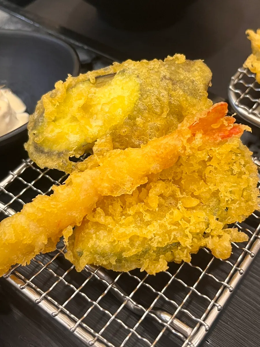 Bowl of udon topped with mushrooms and tempura batter bits