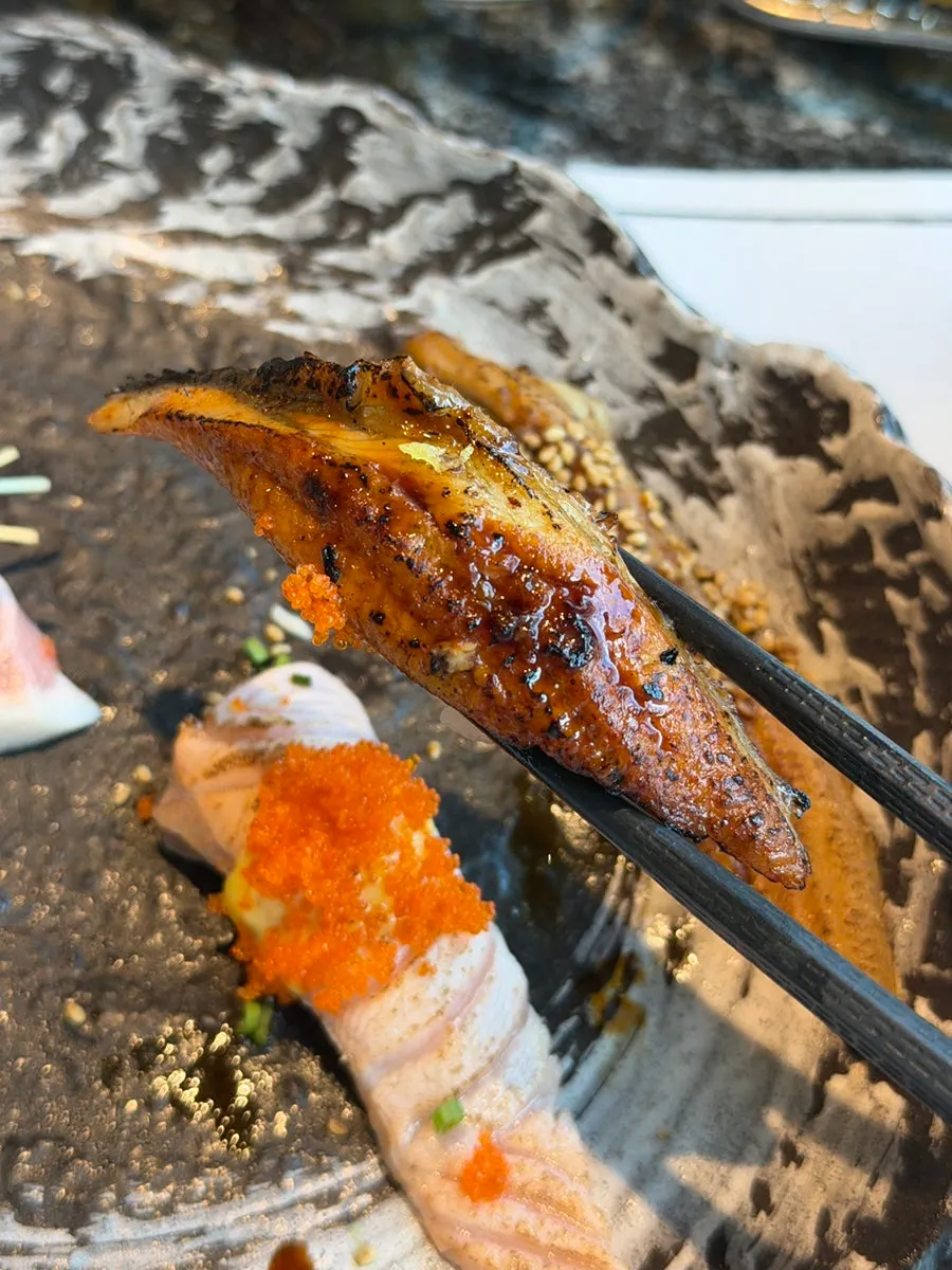 Salmon sushi topped with onion and sauce