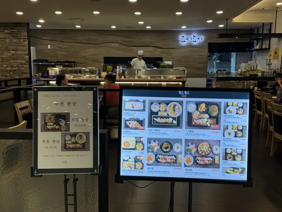 Moshi Moshi menu board listing sushi, udon, and rice bowl sets