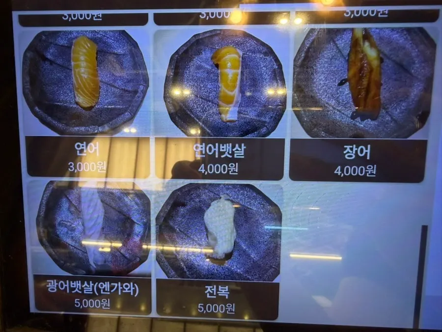 Menu board listing individual sushi and noodle dishes