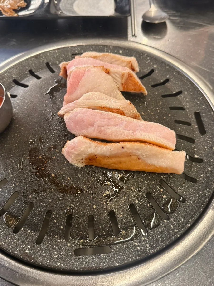 Staff member grilling pork jowl on the plate