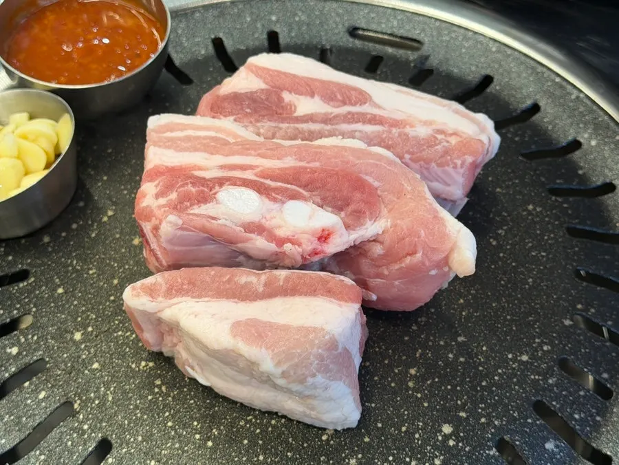 Raw pork ribs and cheonsang pork jowl grilling on the plate