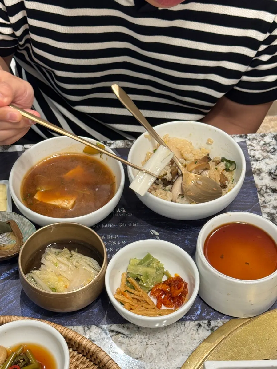 Lunch table with abalone rice, charcoal-grilled seasoned meat, and side dishes