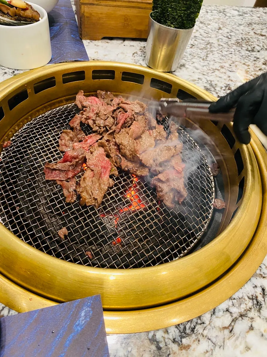 Grilling service stir-frying seasoned hanwoo over charcoal