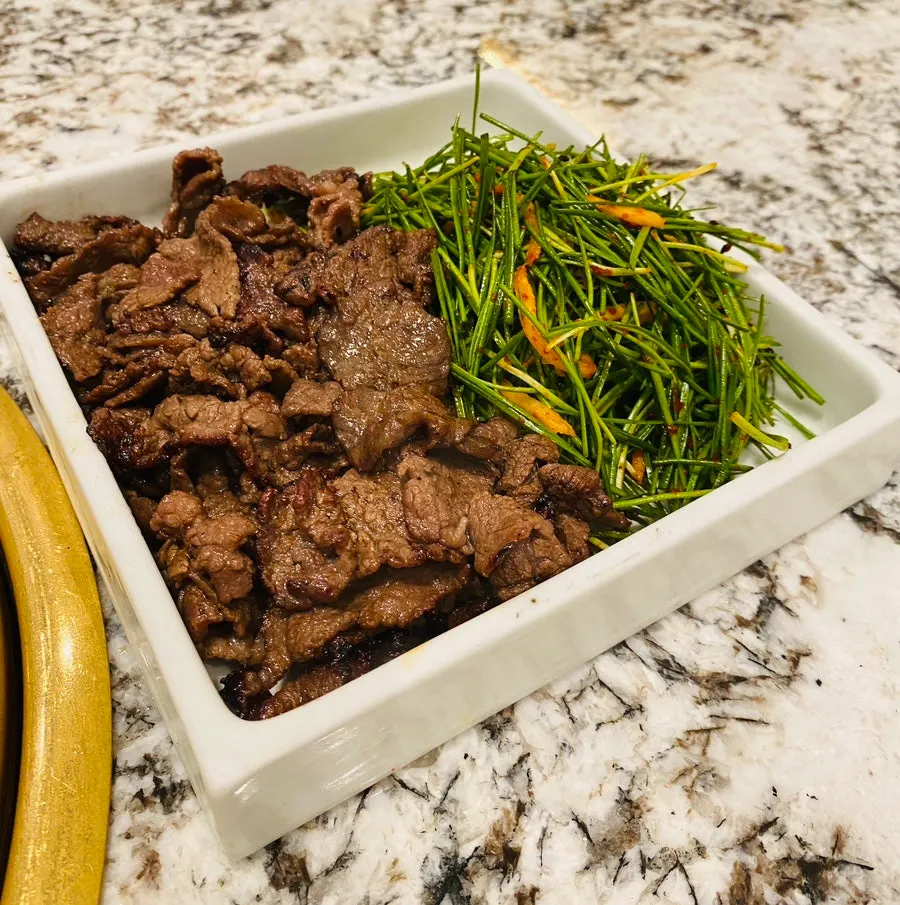 Thinly sliced seasoned beef cooking over charcoal