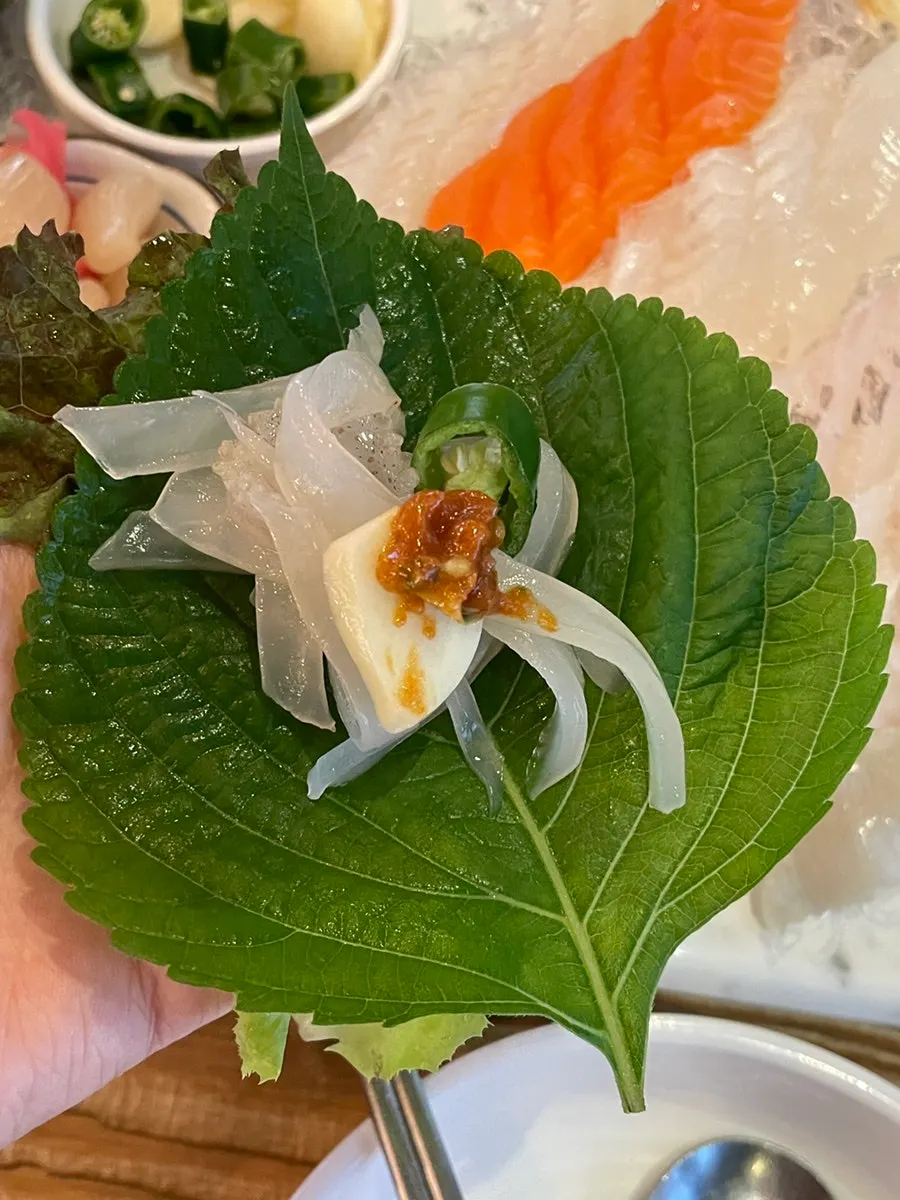 A piece of squid sashimi dipped in chojang sauce
